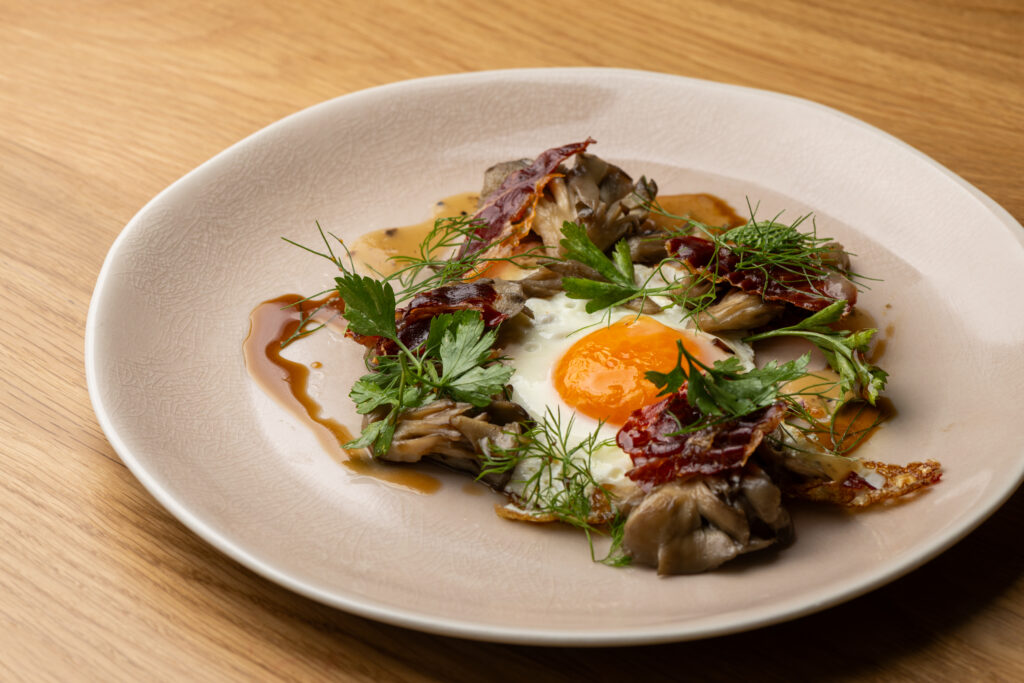 Huevo Roto arrives as egg with maitake mushrooms, jamón, and truffle sauce